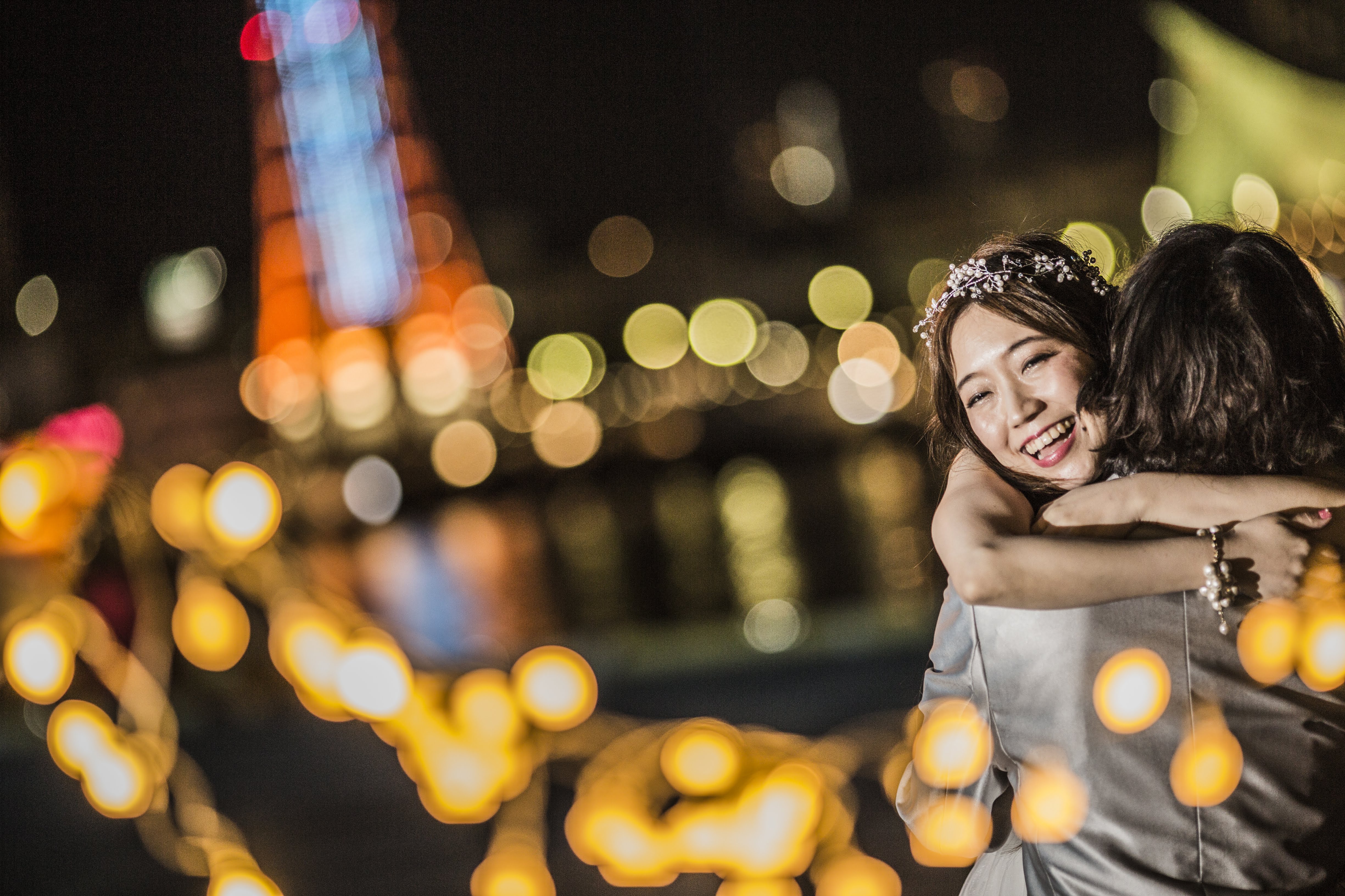 夜の街の光をぼかした背景で、母と子が笑っている